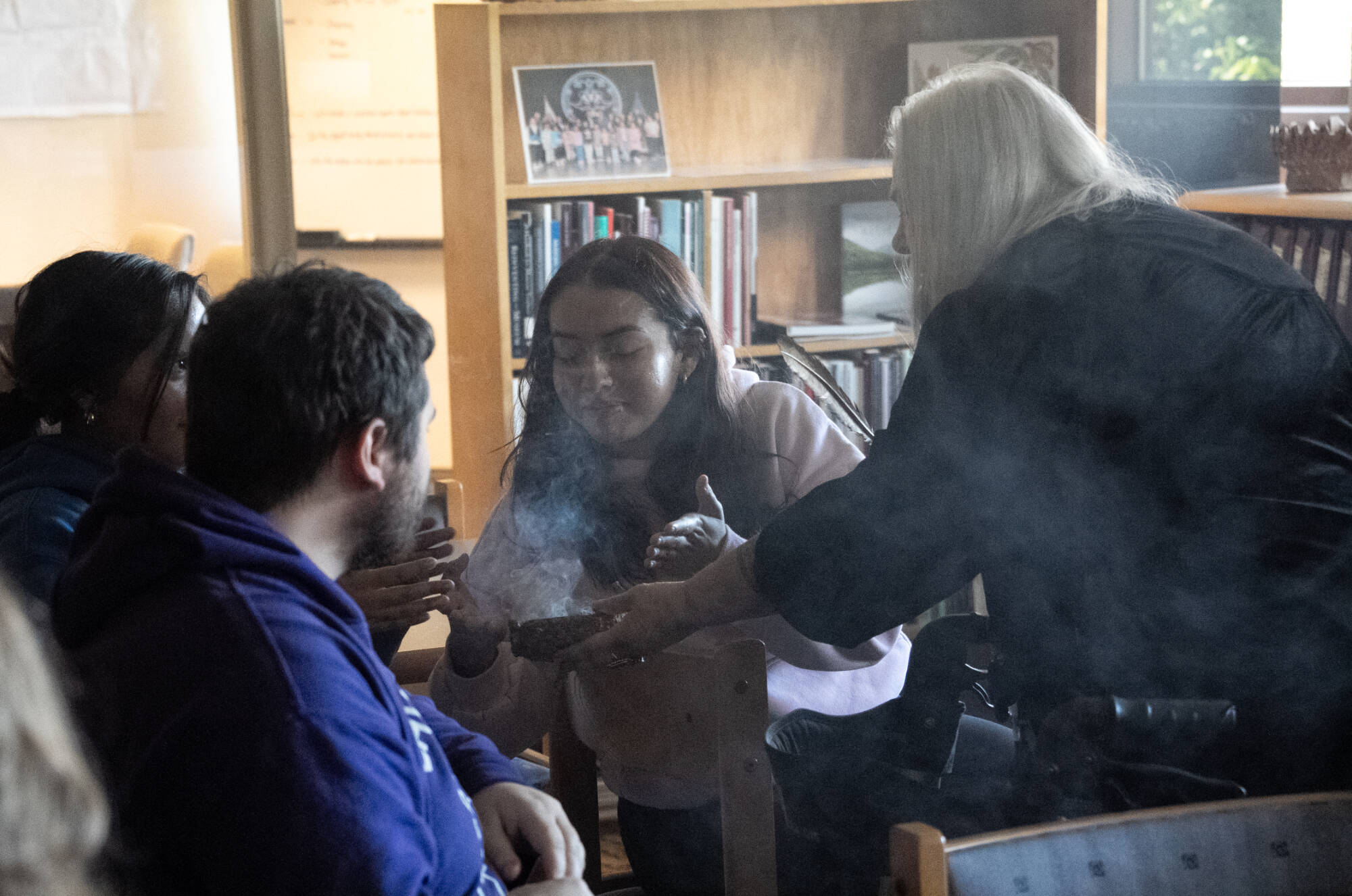 A student receives a smudging blessing from an elder at the Ziibiwing Center
